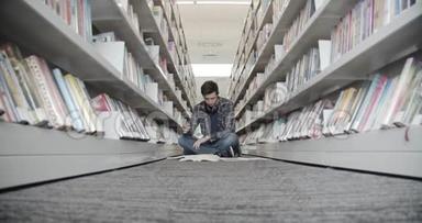 大学生坐在图书馆的地板上，看书。 翻书页